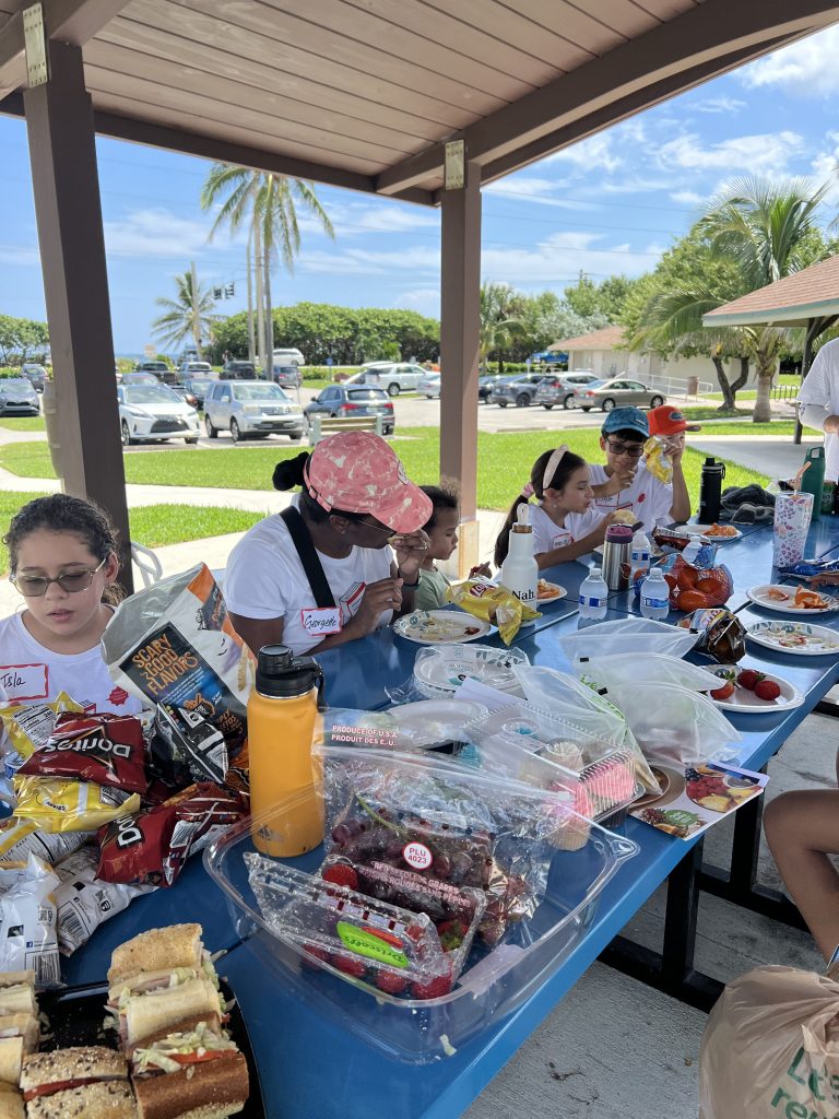 Students of the Vivia Taylor Music Program eat lunch with their families at a beach cleanup.