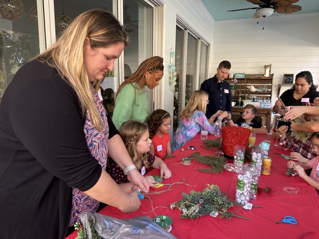 Music students and their families sit together at a table crafting Christmas decorations.