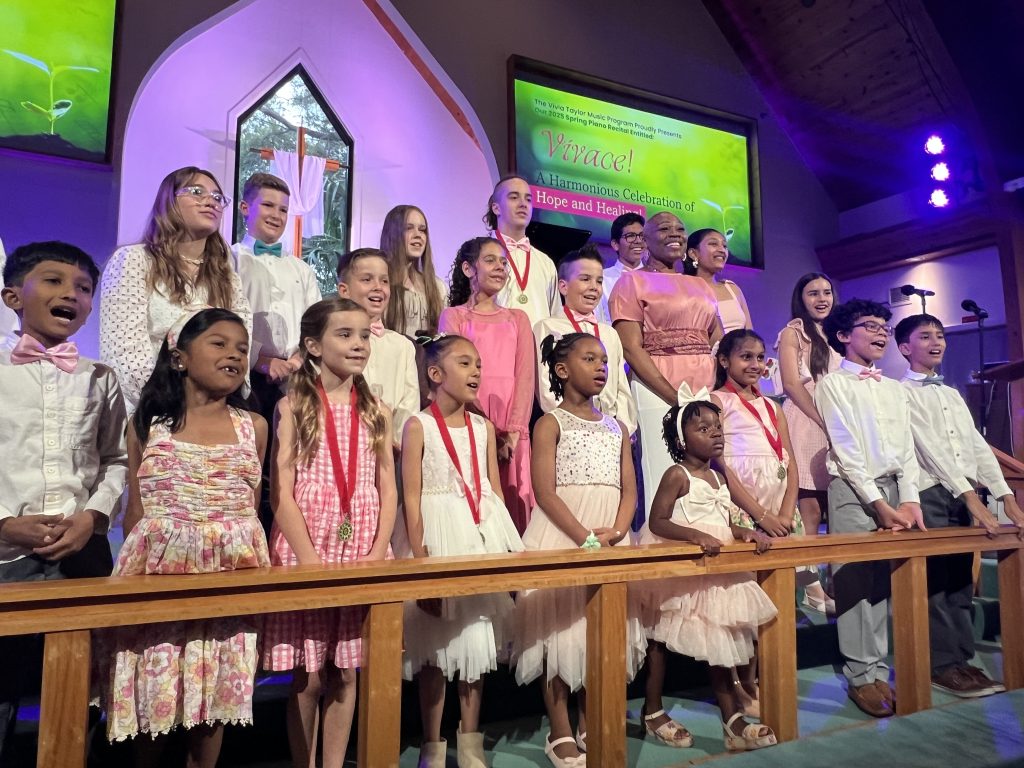 Vivia Taylor with a group of her students singing in a church during a recital.
