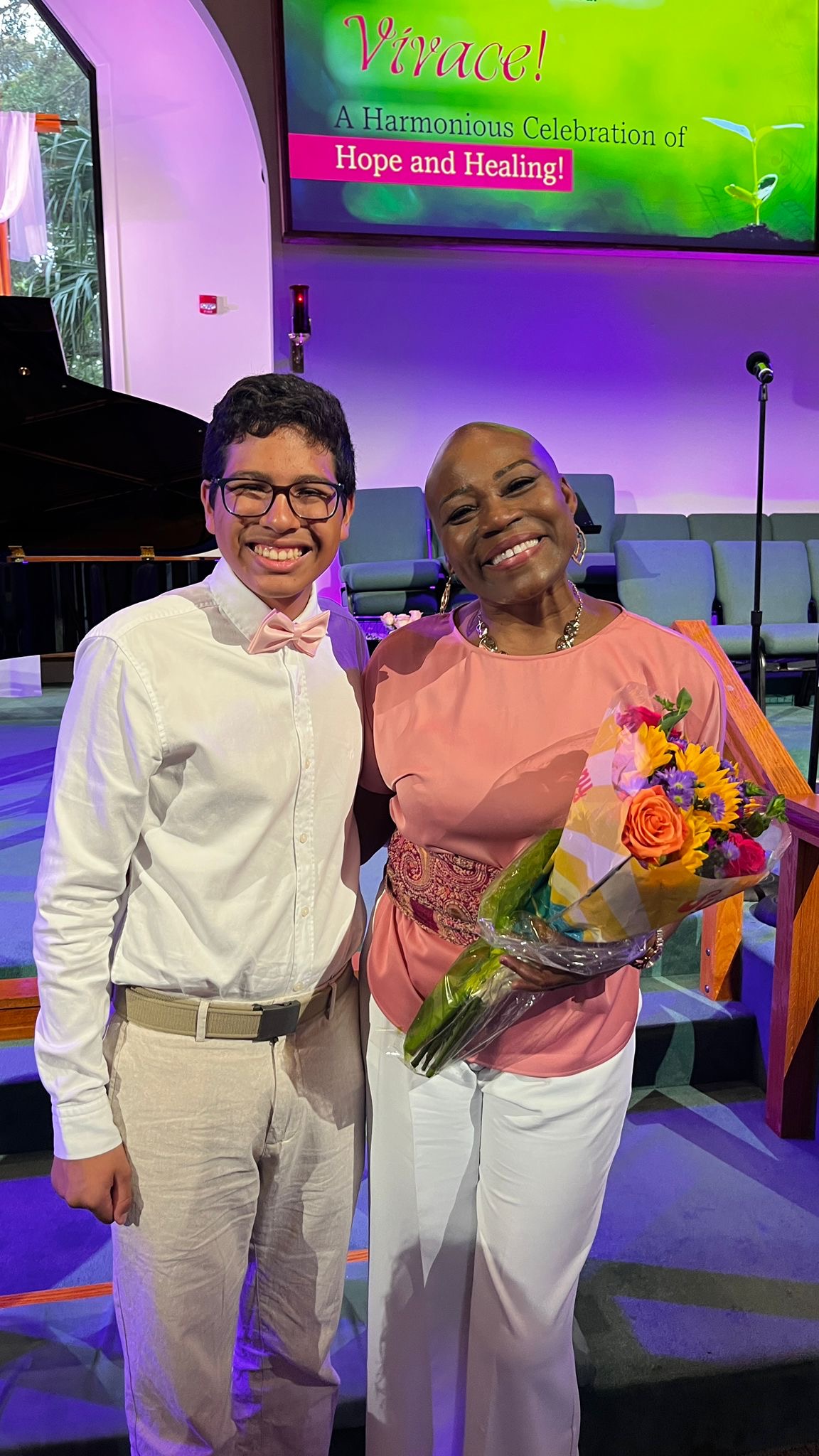 Vivia Taylor holding flowers and standing with a student.