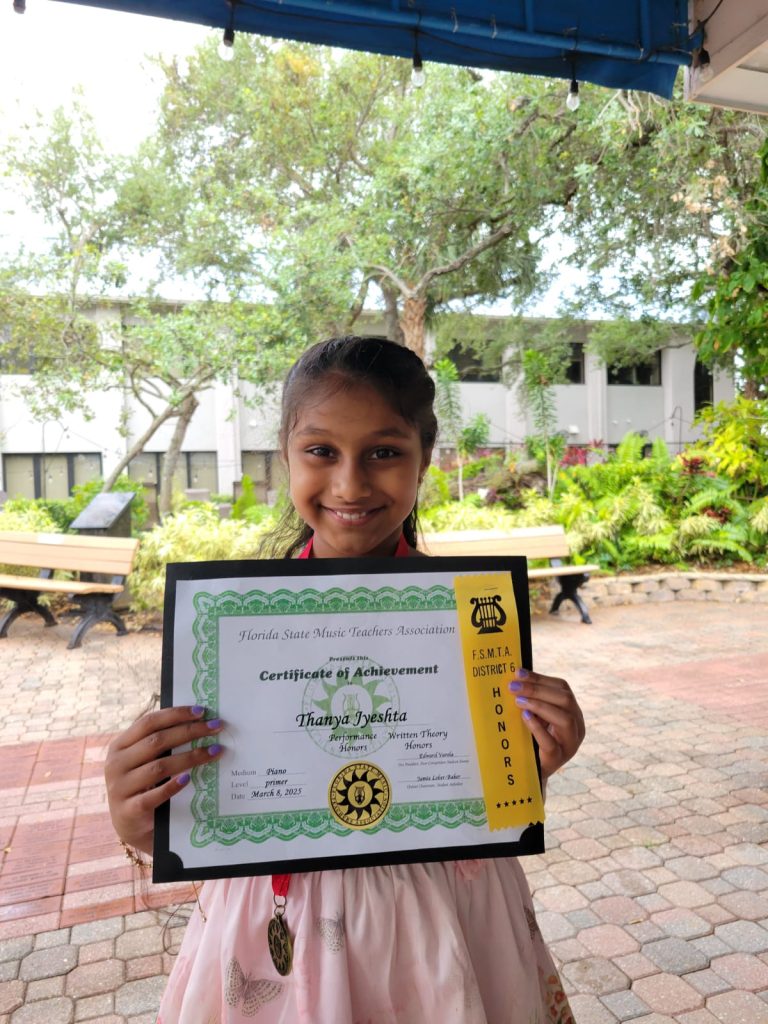 A young music student holds up a certificate of completion.