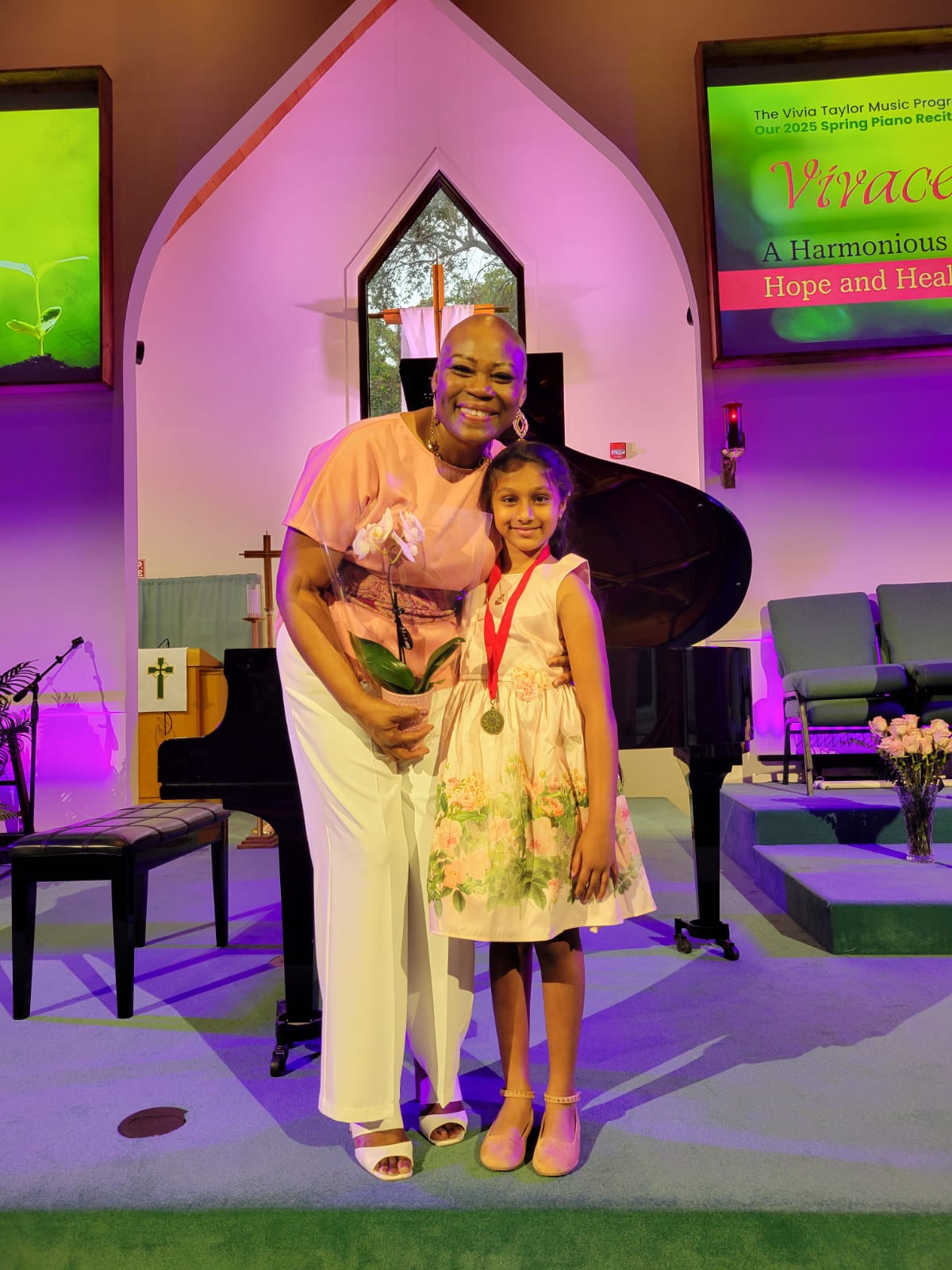 Music teacher Vivia Taylor standing with a student in a church in front of a piano