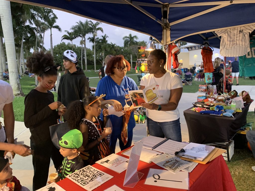 Vivia Taylor talks to a family about her music program at the Wellington Green Market.