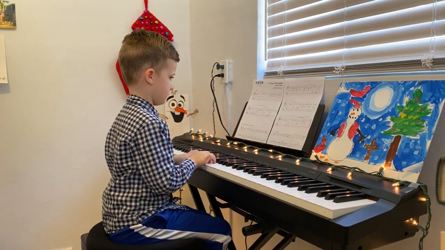 A young piano student sits at a keyboard.