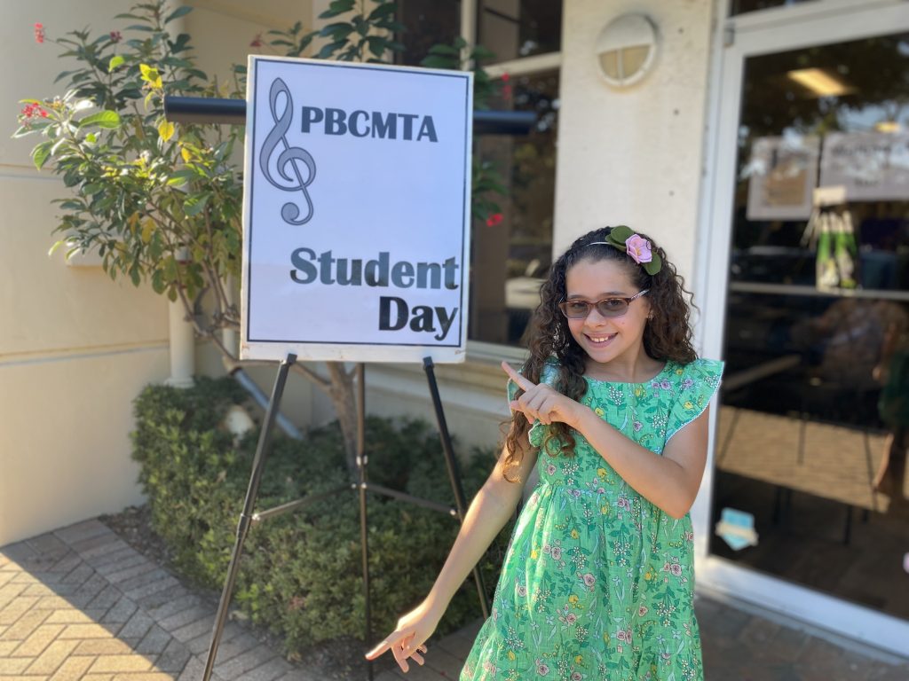 A young music student points to the sign for Student Day.