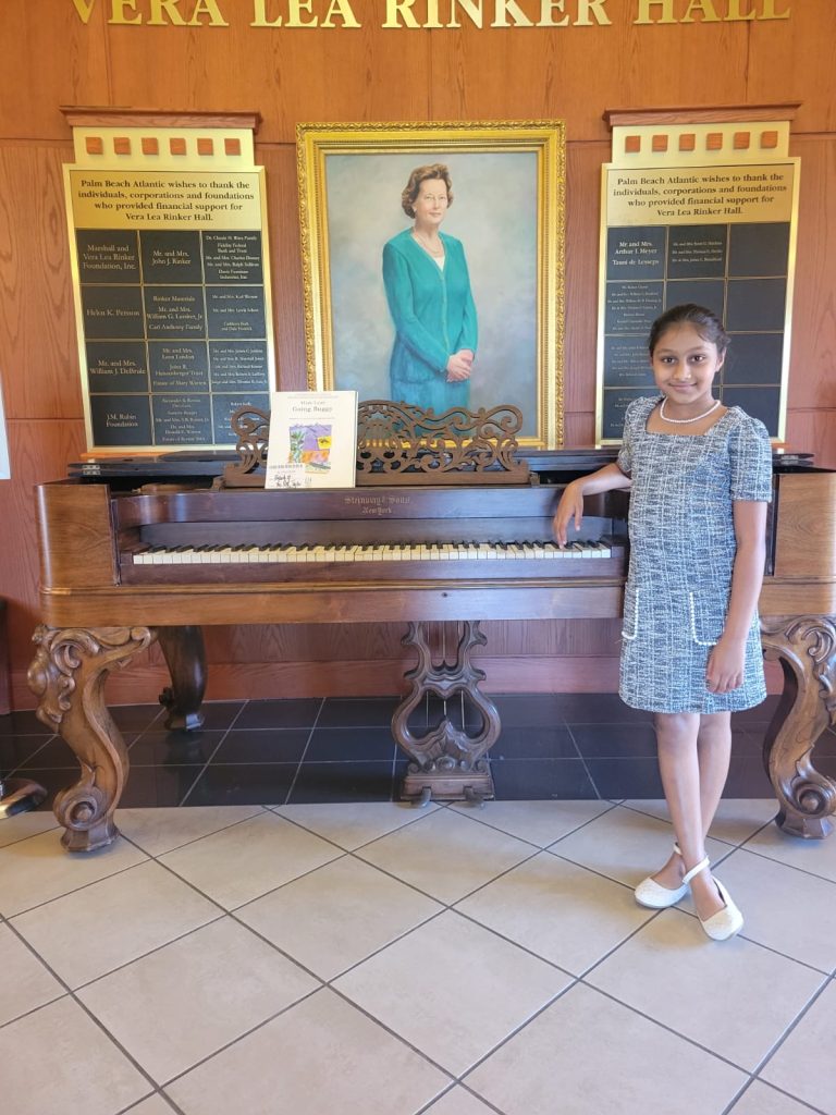 A young music student stands in front of an antique piano.