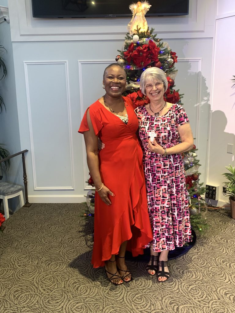 Music teacher Vivia Taylor stands with another woman in front of a Christmas Tree.