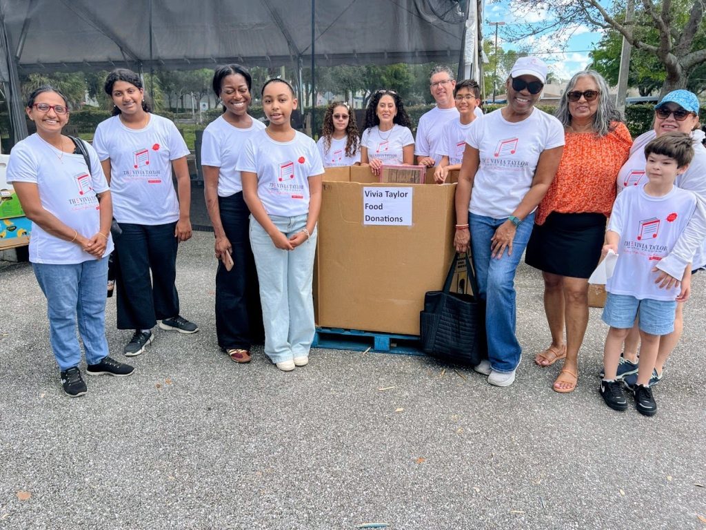 Vivia Taylor stands near a box of donations with her students and their family members.