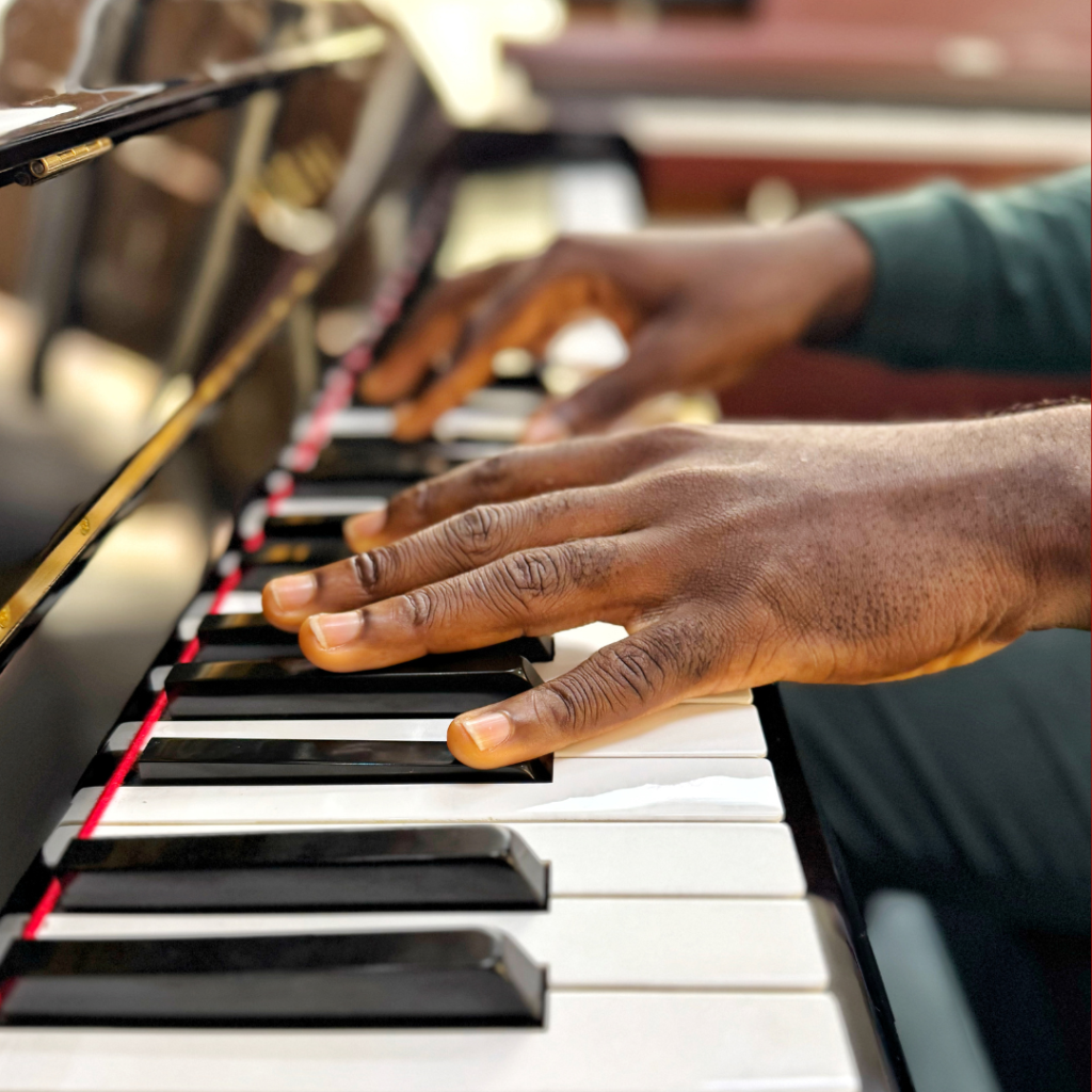 Close-up of an adult's hands with fingers curved on piano keys, demonstrating proper hand position.